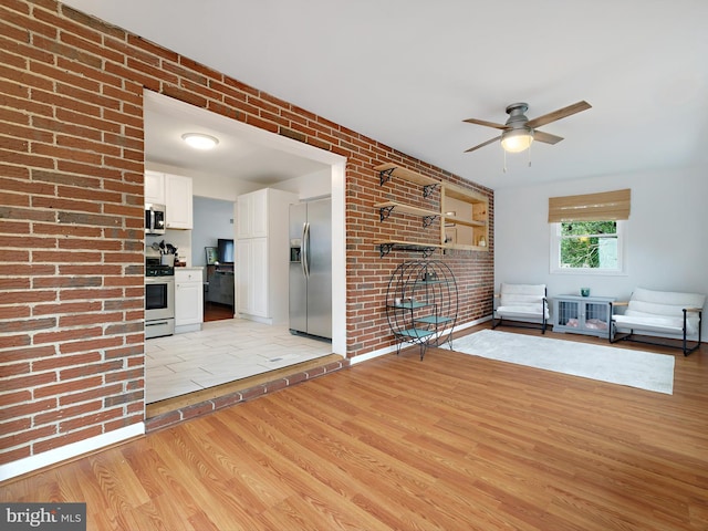 8579 Main Ave, Pasadena, MD 21122 - unfurnished living room with light wood finished floors, brick wall, and a ceiling fan