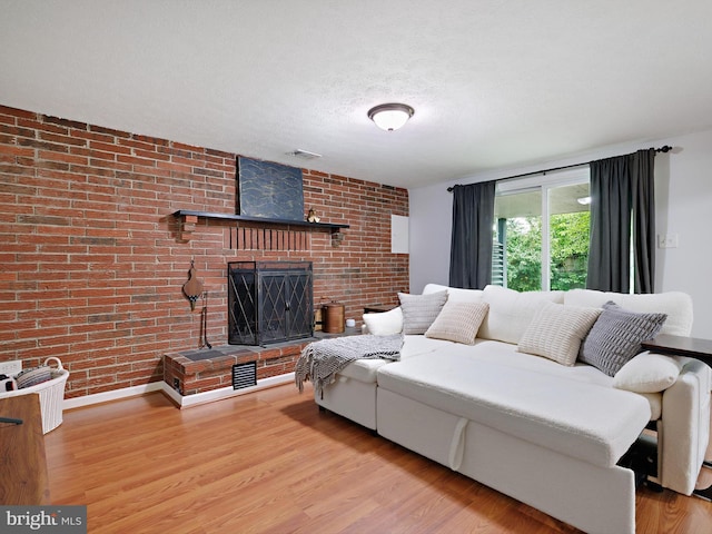 8579 Main Ave, Pasadena, MD 21122 - living room featuring brick wall, a brick fireplace, wood finished floors, and a textured ceiling