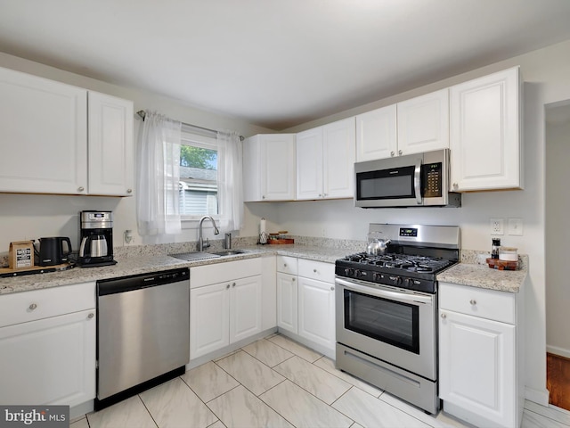 8579 Main Ave, Pasadena, MD 21122 - kitchen featuring appliances with stainless steel finishes, a sink, white cabinetry, and light stone countertops