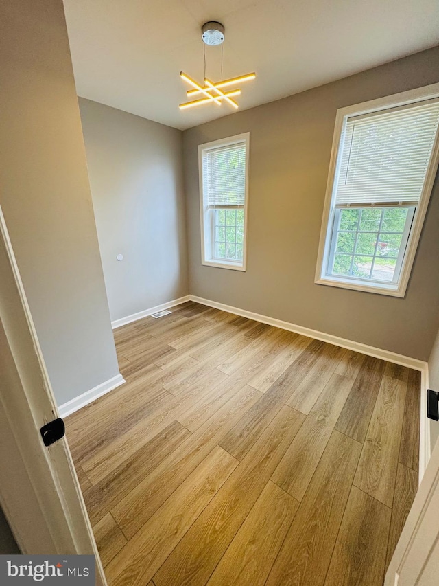 1402 W Saratoga St, Baltimore, MD 21223 - unfurnished room featuring wood finished floors, a chandelier, and baseboards