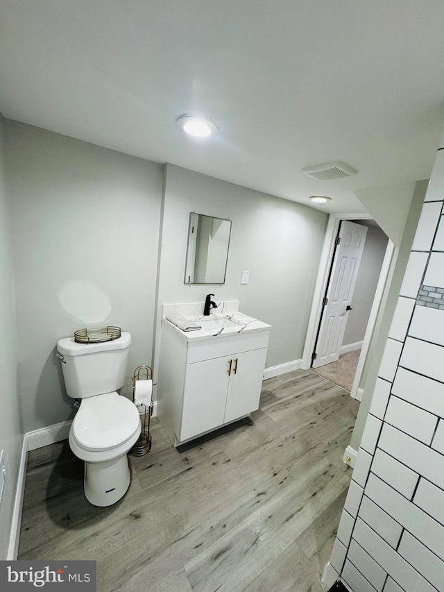 1402 W Saratoga St, Baltimore, MD 21223 - bathroom with wood finished floors, vanity, toilet, and baseboards