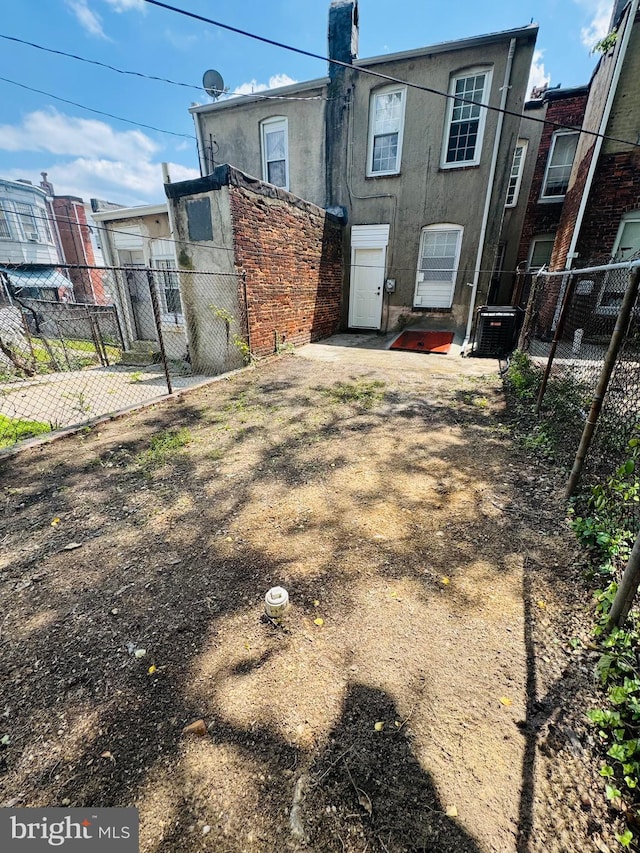 1402 W Saratoga St, Baltimore, MD 21223 - back of house with stucco siding, cooling unit, and a chimney