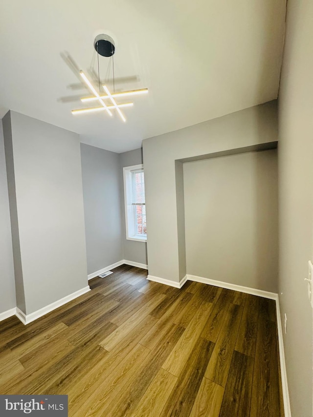 1402 W Saratoga St, Baltimore, MD 21223 - unfurnished room featuring wood finished floors, baseboards, and a chandelier