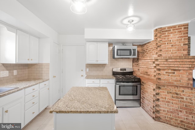 8007 Lewinsville Rd, Mclean, VA 22102 - kitchen featuring appliances with stainless steel finishes, light tile patterned flooring, decorative backsplash, white cabinets, and brick wall