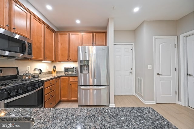 15255 Leicestershire St, Woodbridge, VA 22191 - kitchen featuring appliances with stainless steel finishes, dark stone countertops, brown cabinets, and recessed lighting