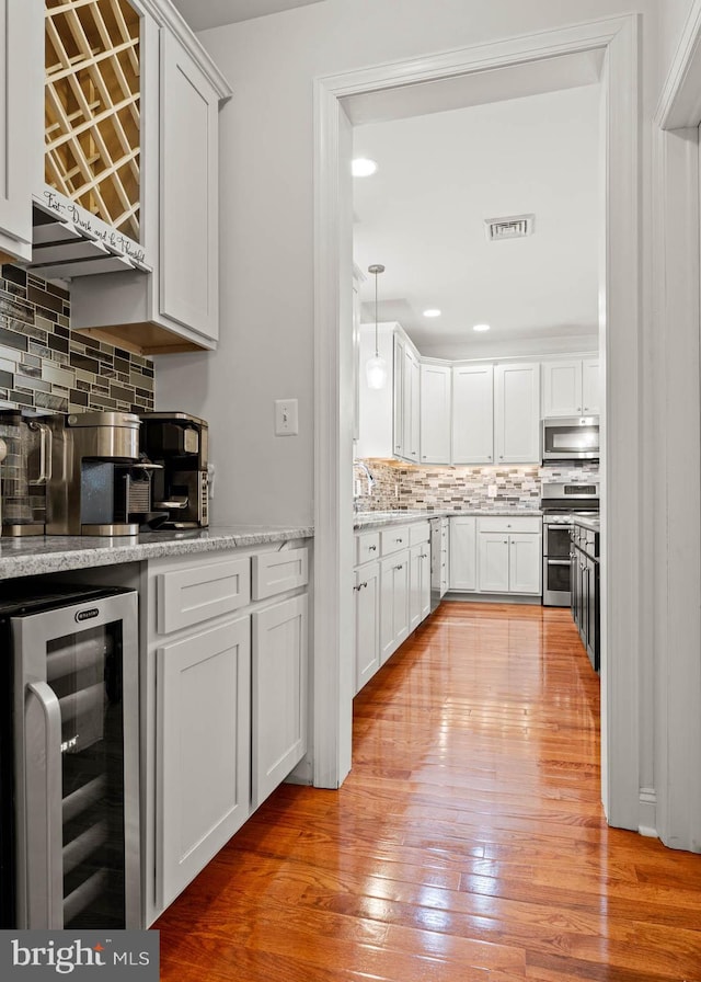255 Summit Ave, Conshohocken, PA 19428 - kitchen with wine cooler, stainless steel appliances, backsplash, light wood-style flooring, and white cabinets