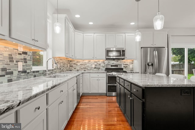 255 Summit Ave, Conshohocken, PA 19428 - kitchen featuring stainless steel appliances, a sink, white cabinetry, light wood-style floors, and hanging light fixtures