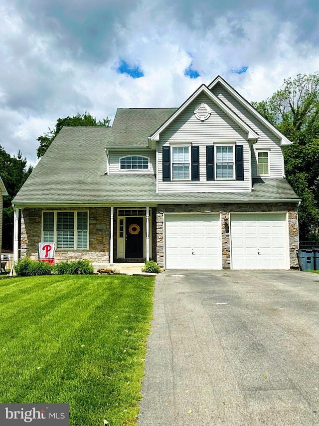 905 Milmont Ave, Swarthmore, PA 19081 - view of front of home with stone siding, a garage, asphalt driveway, and a front yard