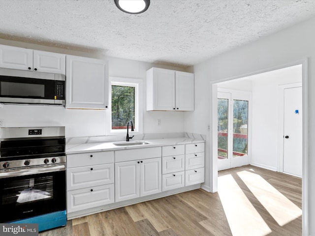 153 Bear Track Rd, Augusta, WV 26704 - kitchen featuring appliances with stainless steel finishes, a sink, light countertops, light wood-style floors, and a textured ceiling
