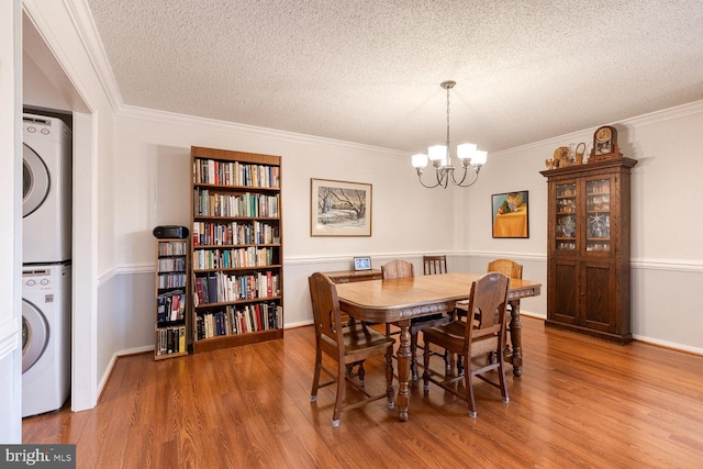 4100 N Charles St Unit 203, Baltimore, MD 21218 - dining room featuring stacked washer / dryer, a chandelier, wood finished floors, a textured ceiling, and crown molding