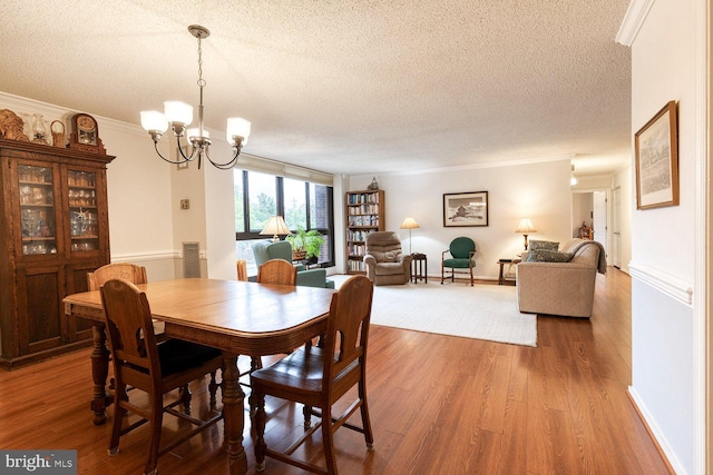 4100 N Charles St Unit 203, Baltimore, MD 21218 - dining space with a textured ceiling, wood finished floors, a chandelier, ornamental molding, and baseboards