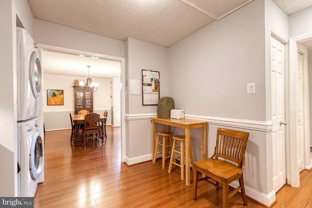 4100 N Charles St Unit 203, Baltimore, MD 21218 - laundry area featuring stacked washer and clothes dryer, wood finished floors, baseboards, a chandelier, and a textured ceiling