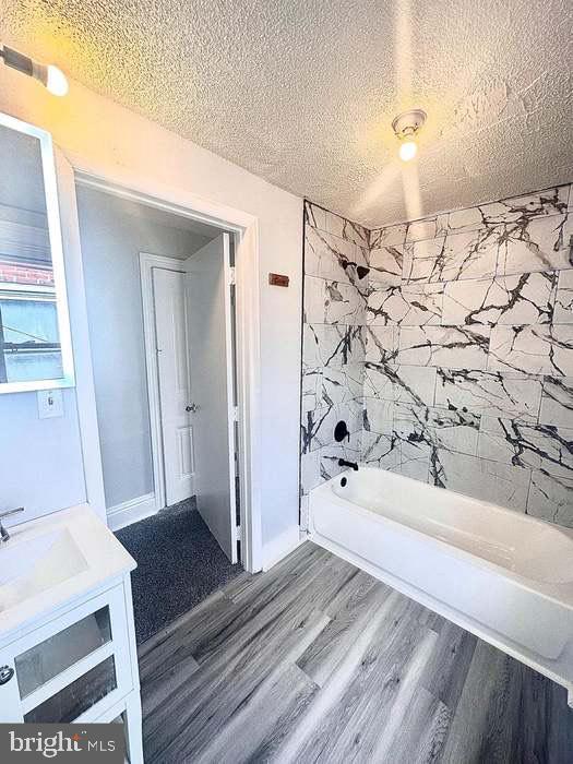 1035 N Pine St, Wilmington, DE 19801 - bathroom featuring wood finished floors, vanity, bathing tub / shower combination, and a textured ceiling