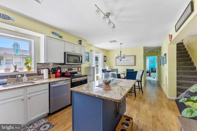 25 N 12th St, Del Haven, NJ 08251 - kitchen with stainless steel appliances, a sink, light wood-style flooring, white cabinets, and decorative light fixtures