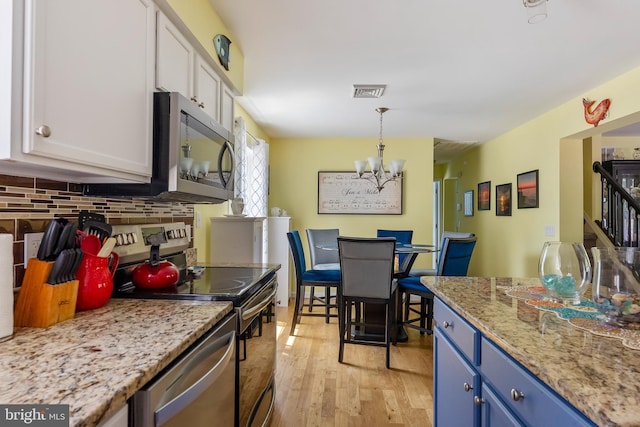 25 N 12th St, Del Haven, NJ 08251 - kitchen with stainless steel appliances, blue cabinetry, tasteful backsplash, light wood finished floors, and a chandelier