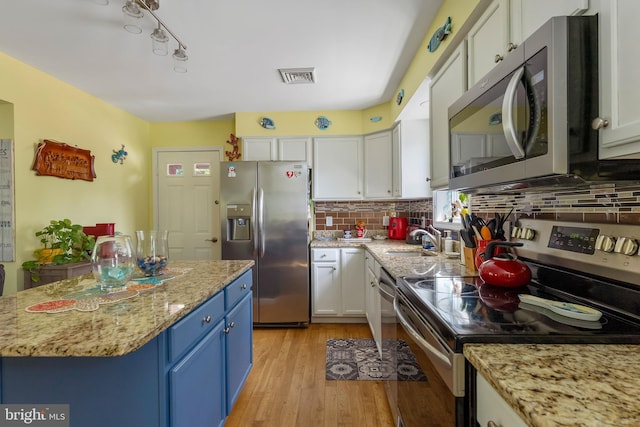 25 N 12th St, Del Haven, NJ 08251 - kitchen with appliances with stainless steel finishes, blue cabinetry, a sink, white cabinetry, and tasteful backsplash