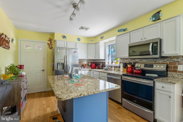 25 N 12th St, Del Haven, NJ 08251 - kitchen with stainless steel appliances, white cabinetry, decorative backsplash, light wood-style floors, and light stone counters