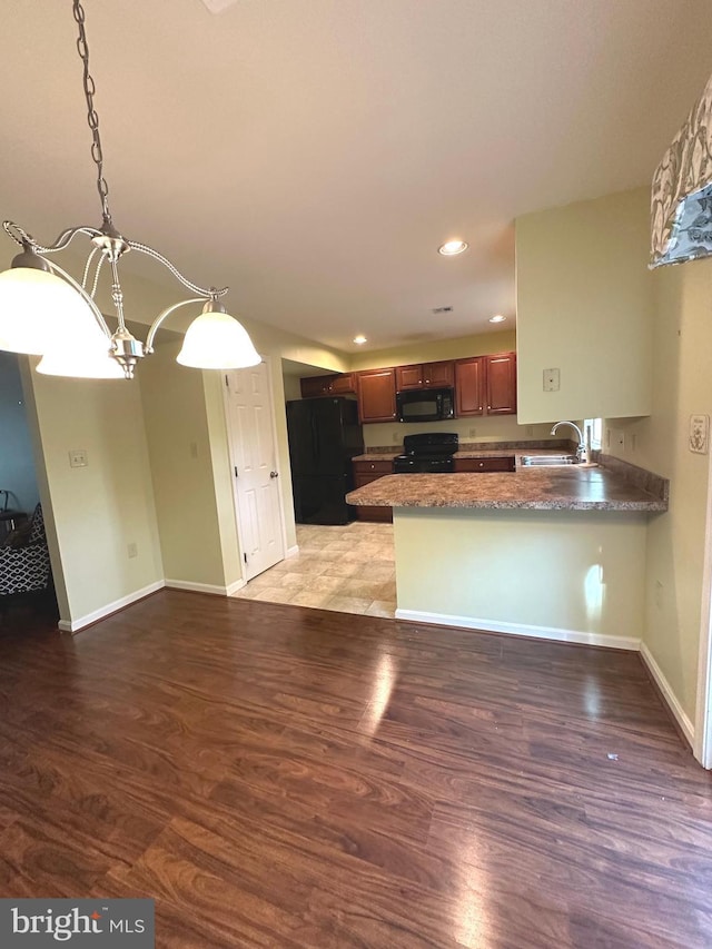 413 Park View Dr, Harrisburg, PA 17110 - kitchen with black appliances, a sink, a chandelier, wood finished floors, and a peninsula
