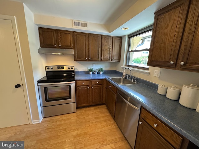 315 S Valley Forge Rd Unit 7, Devon, PA 19333 - kitchen with stainless steel appliances, a sink, under cabinet range hood, dark countertops, and light wood-style floors