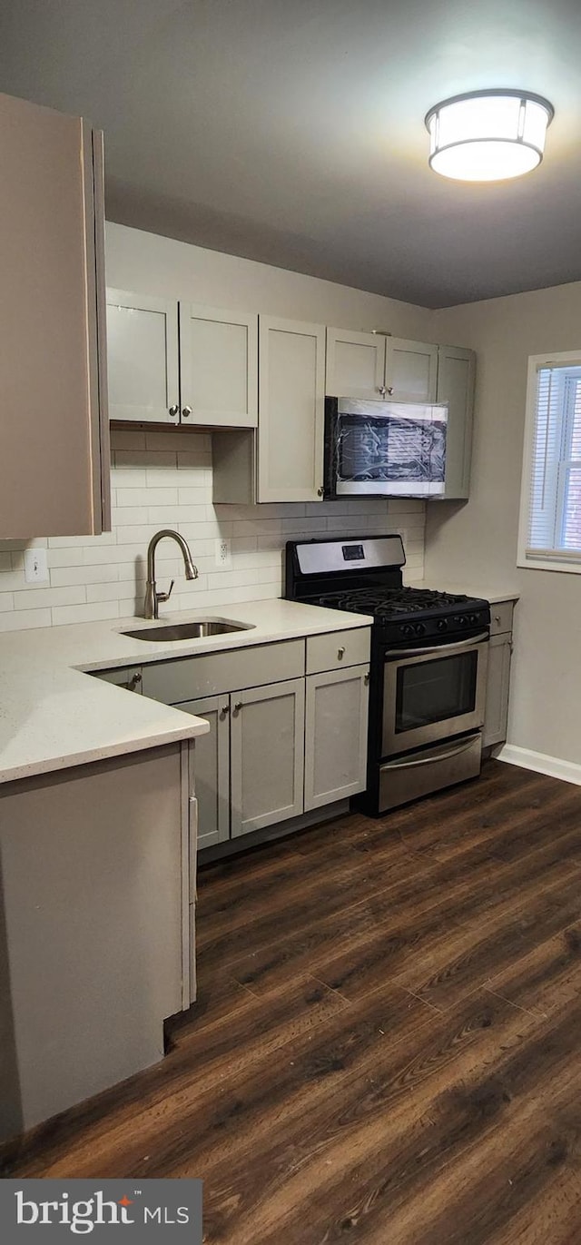 538 Mcmechen St, Baltimore, MD 21217 - kitchen with appliances with stainless steel finishes, a sink, dark wood-type flooring, light countertops, and tasteful backsplash