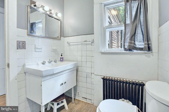 134 N Plum St, Lancaster, PA 17602 - bathroom with radiator, tile walls, toilet, vanity, and wood finished floors