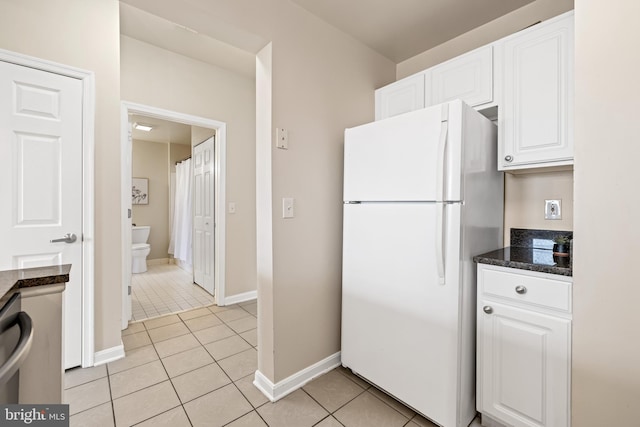 23 Pierside Dr Unit 429, Baltimore, MD 21230 - kitchen featuring freestanding refrigerator, light tile patterned floors, white cabinetry, dark stone counters, and baseboards
