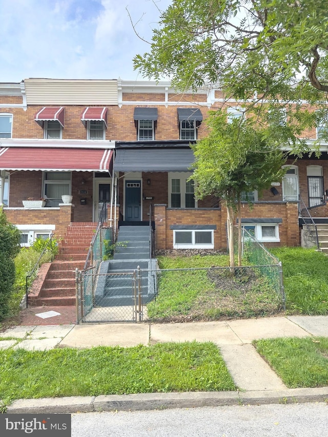 1736 E 30th St, Baltimore, MD 21218 - townhome / multi-family property featuring brick siding, a fenced front yard, and stairs