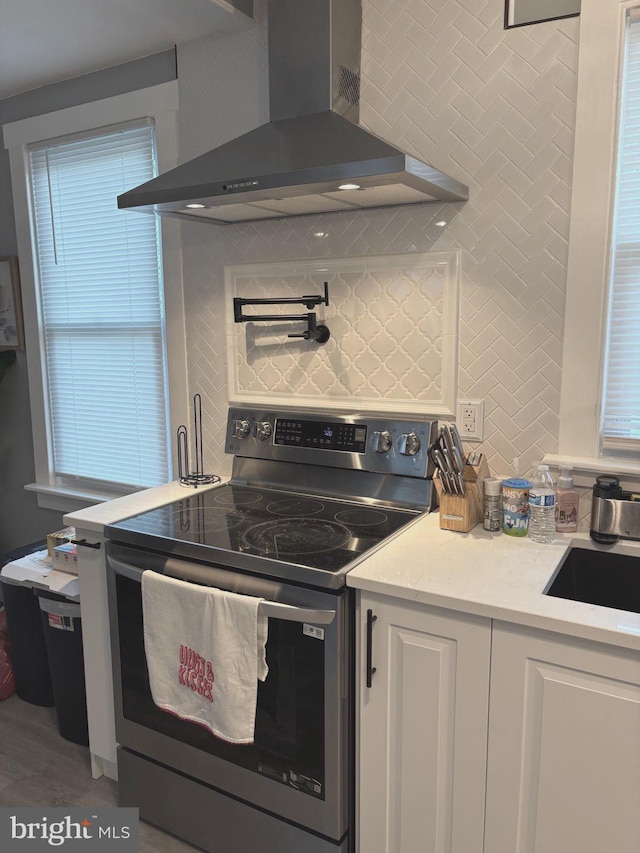 3258 N 48th St, Pennsauken, NJ 08109 - kitchen featuring wall chimney range hood, electric range, backsplash, and white cabinets