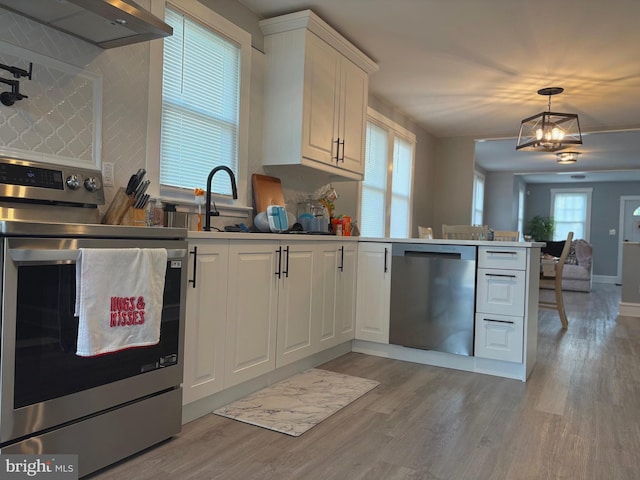 3258 N 48th St, Pennsauken, NJ 08109 - kitchen featuring stainless steel appliances, ventilation hood, a peninsula, white cabinets, and light wood-style floors