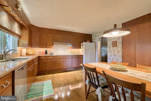 1545 Farr Rd, Wyomissing, PA 19610 - kitchen with stainless steel dishwasher, under cabinet range hood, a sink, freestanding refrigerator, and a textured ceiling