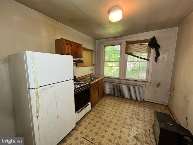 510 62nd Ave, Capitol Heights, MD 20743 - kitchen with freestanding refrigerator, gas range oven, radiator heating unit, under cabinet range hood, and brown cabinetry