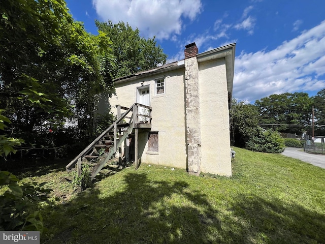 510 62nd Ave, Capitol Heights, MD 20743 - view of home's exterior with a chimney, stucco siding, a yard, and stairway