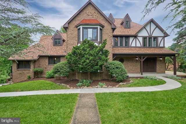 7423 Round Hill Rd, Frederick, MD 21702 - tudor house with a front yard, brick siding, a porch, and a shingled roof