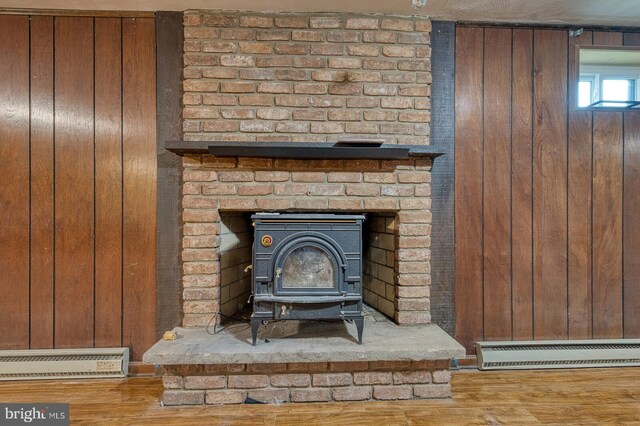7423 Round Hill Rd, Frederick, MD 21702 - detailed view of baseboard heating, a wood stove, wooden walls, and wood finished floors