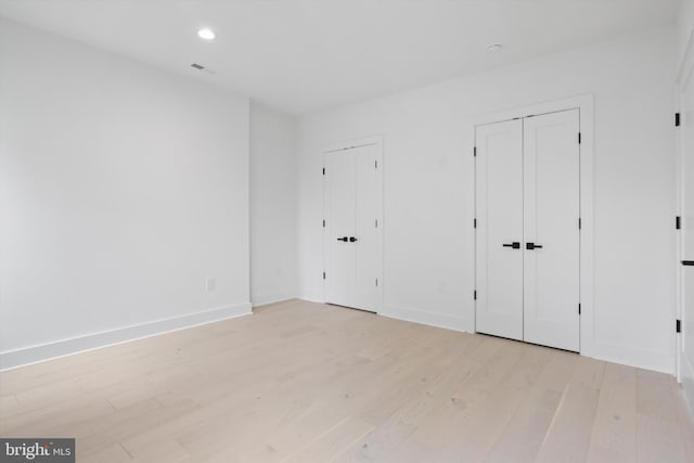 2007 S Joyce St, Arlington, VA 22202 - unfurnished bedroom with multiple closets, light wood finished floors, baseboards, and recessed lighting