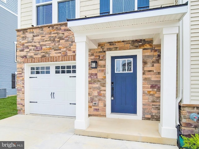 118 Fletcher Cir, Middletown, DE 19709 - entrance to property featuring stone siding, an attached garage, cooling unit, and concrete driveway