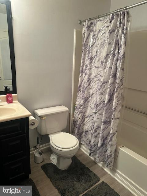 6708 Pauline Ct, Bryans Road, MD 20616 - full bath featuring wood finished floors, toilet, vanity, shower / bath combination with curtain, and baseboards