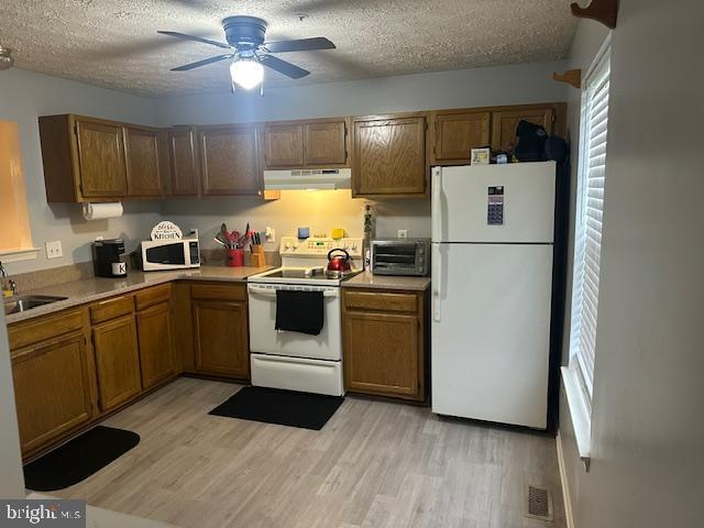6708 Pauline Ct, Bryans Road, MD 20616 - kitchen with white appliances, under cabinet range hood, a textured ceiling, light wood-style floors, and brown cabinets