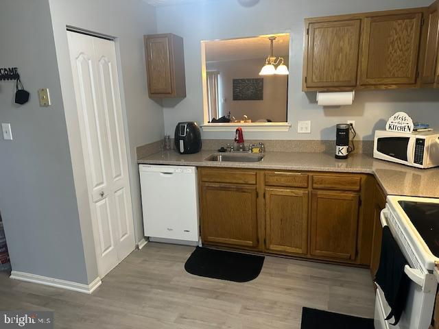 6708 Pauline Ct, Bryans Road, MD 20616 - kitchen with white appliances, a sink, light wood-type flooring, light countertops, and brown cabinets