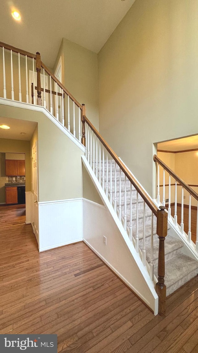 9 Whirlaway Dr, Bear, DE 19701 - staircase with wood finished floors, a wainscoted wall, a towering ceiling, and recessed lighting