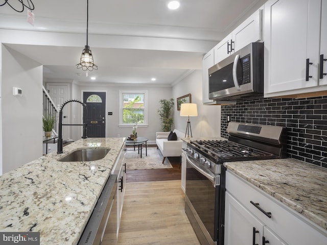 5623 Eads St NE, Washington, DC 20019 - kitchen featuring appliances with stainless steel finishes, a sink, ornamental molding, light wood-style floors, and tasteful backsplash