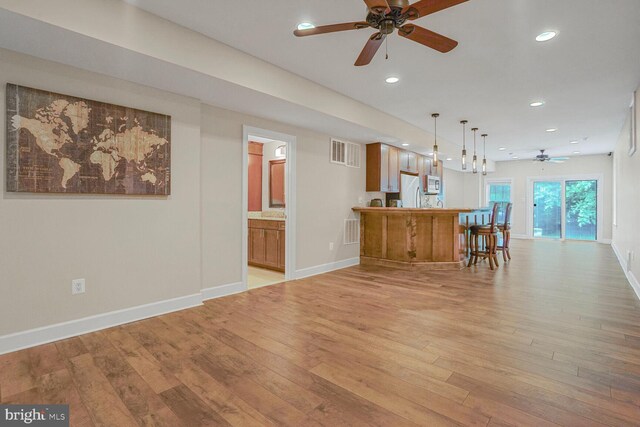 4904 Charmed Ct, Woodbridge, VA 22192 - kitchen featuring a ceiling fan, white microwave, brown cabinetry, light wood-style floors, and a peninsula