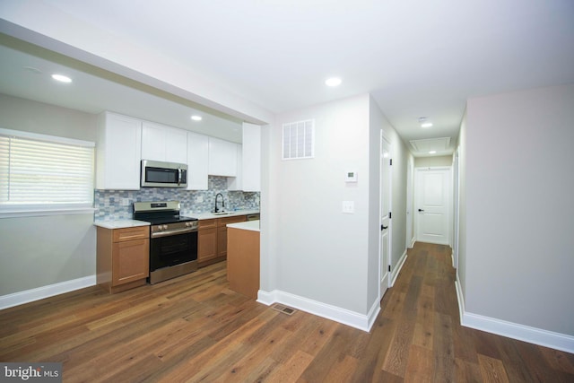 1407 Ruatan St, Hyattsville, MD 20783 - kitchen featuring stainless steel appliances, a sink, light countertops, dark wood-type flooring, and tasteful backsplash