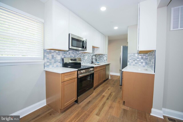 1407 Ruatan St, Hyattsville, MD 20783 - kitchen with appliances with stainless steel finishes, a sink, wood finished floors, light countertops, and backsplash