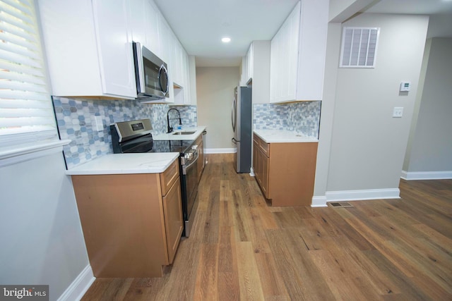 1407 Ruatan St, Hyattsville, MD 20783 - kitchen featuring stainless steel appliances, a sink, brown cabinetry, white cabinets, and recessed lighting
