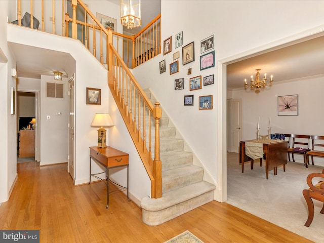 2409 Bear Den Rd, Frederick, MD 21701 - stairway featuring a chandelier, wood finished floors, baseboards, and a high ceiling