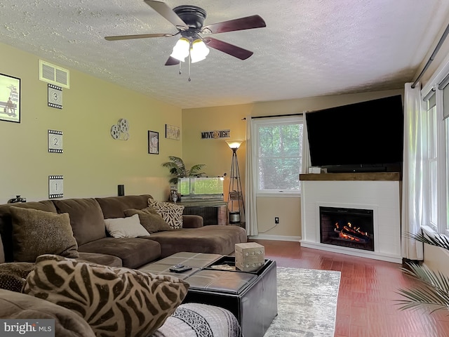 24950 Morgan Rd, Hollywood, MD 20636 - living room featuring wood finished floors, a textured ceiling, a large fireplace, a ceiling fan, and baseboards