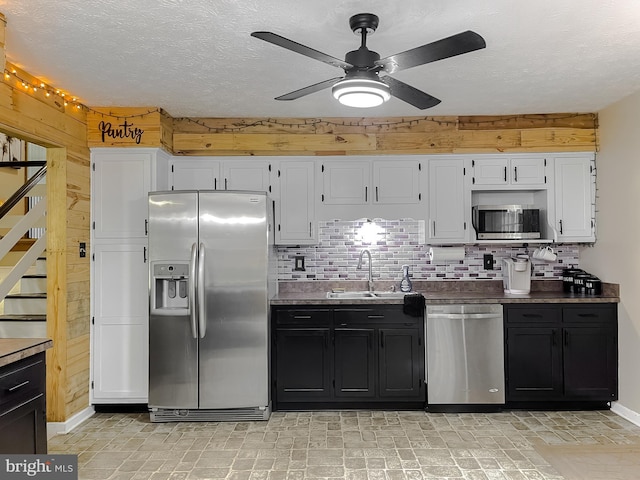24950 Morgan Rd, Hollywood, MD 20636 - kitchen featuring stainless steel appliances, wood walls, a sink, ceiling fan, and white cabinets