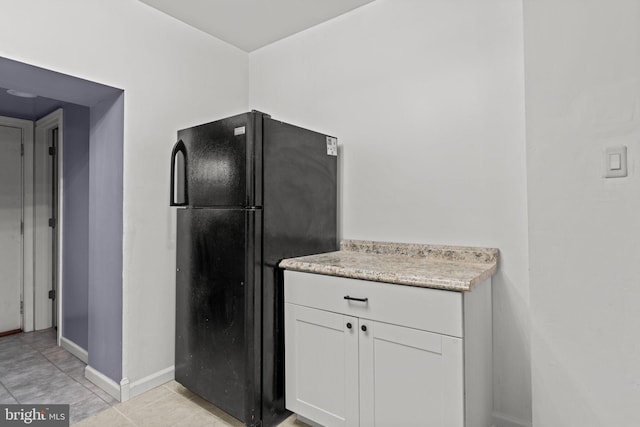 1504 N 57th St, Philadelphia, PA 19131 - kitchen with freestanding refrigerator, white cabinetry, baseboards, light tile patterned floors, and light stone countertops
