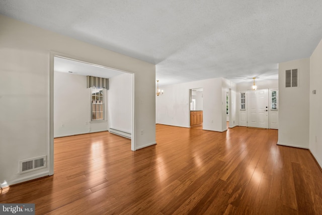2516 N Haven Cv, Annapolis, MD 21401 - unfurnished living room featuring a baseboard radiator, a chandelier, wood finished floors, baseboards, and a textured ceiling